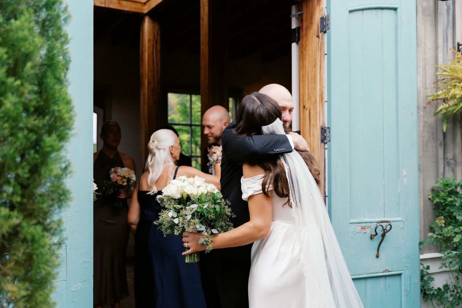 A couple shares a romantic moment outside a rustic blue door during their wedding photoshoot.