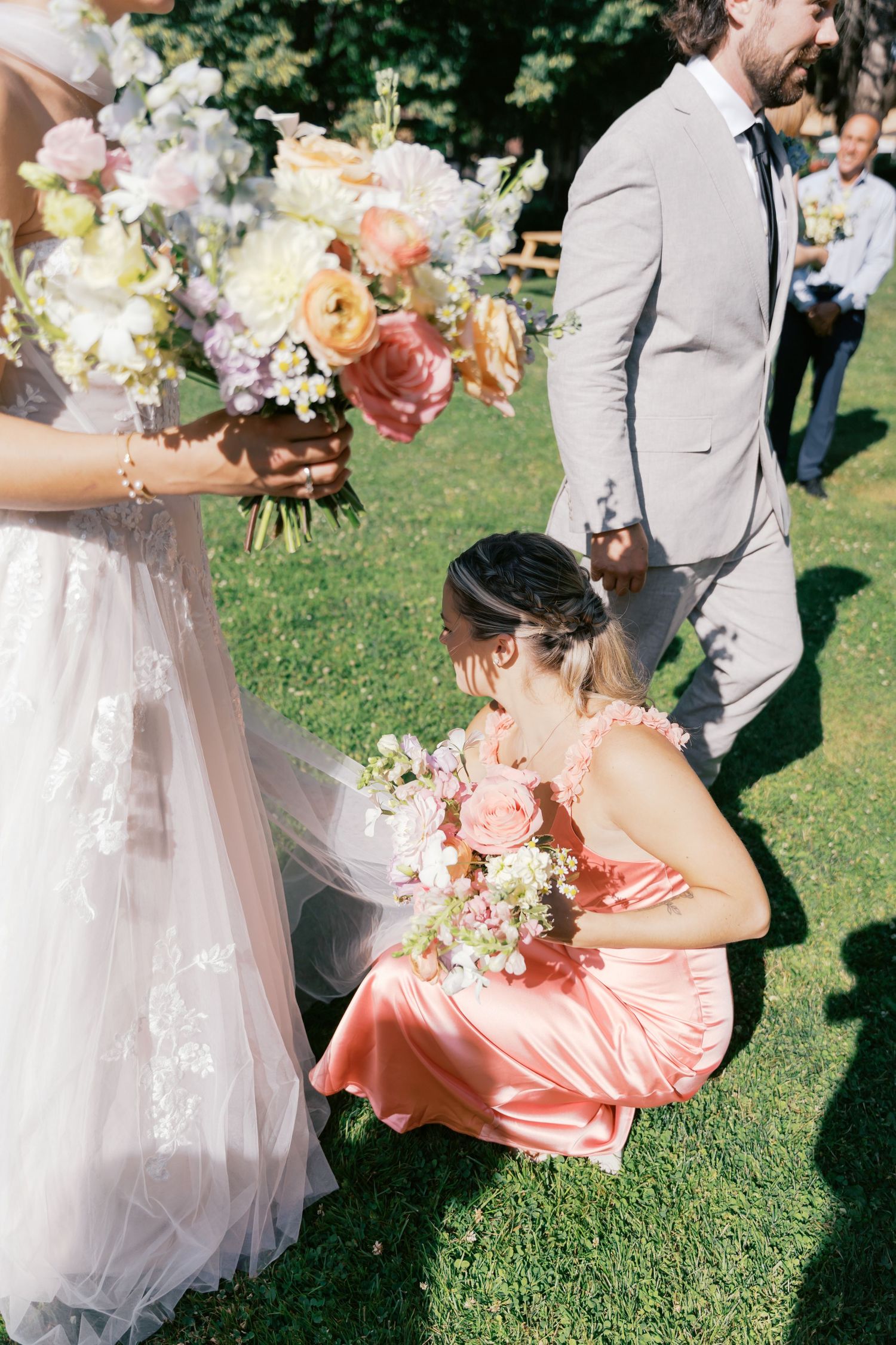Wedding couple shares intimate moment with floral bouquet in sunny garden setting.
