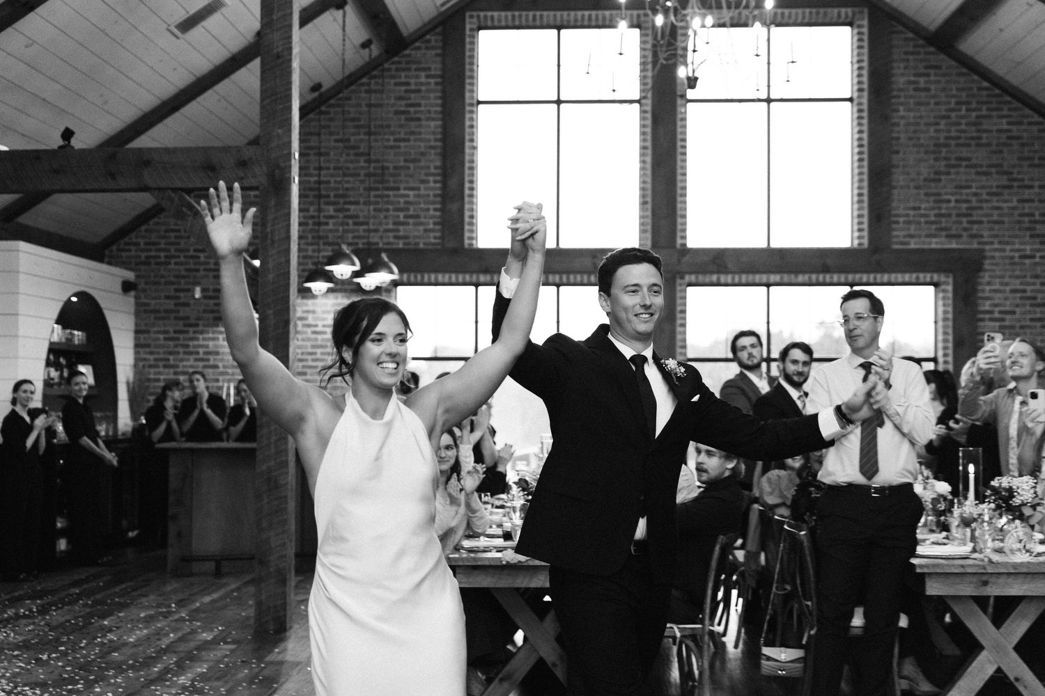 Wedding reception celebration inside a bright modern venue with exposed wooden beams.