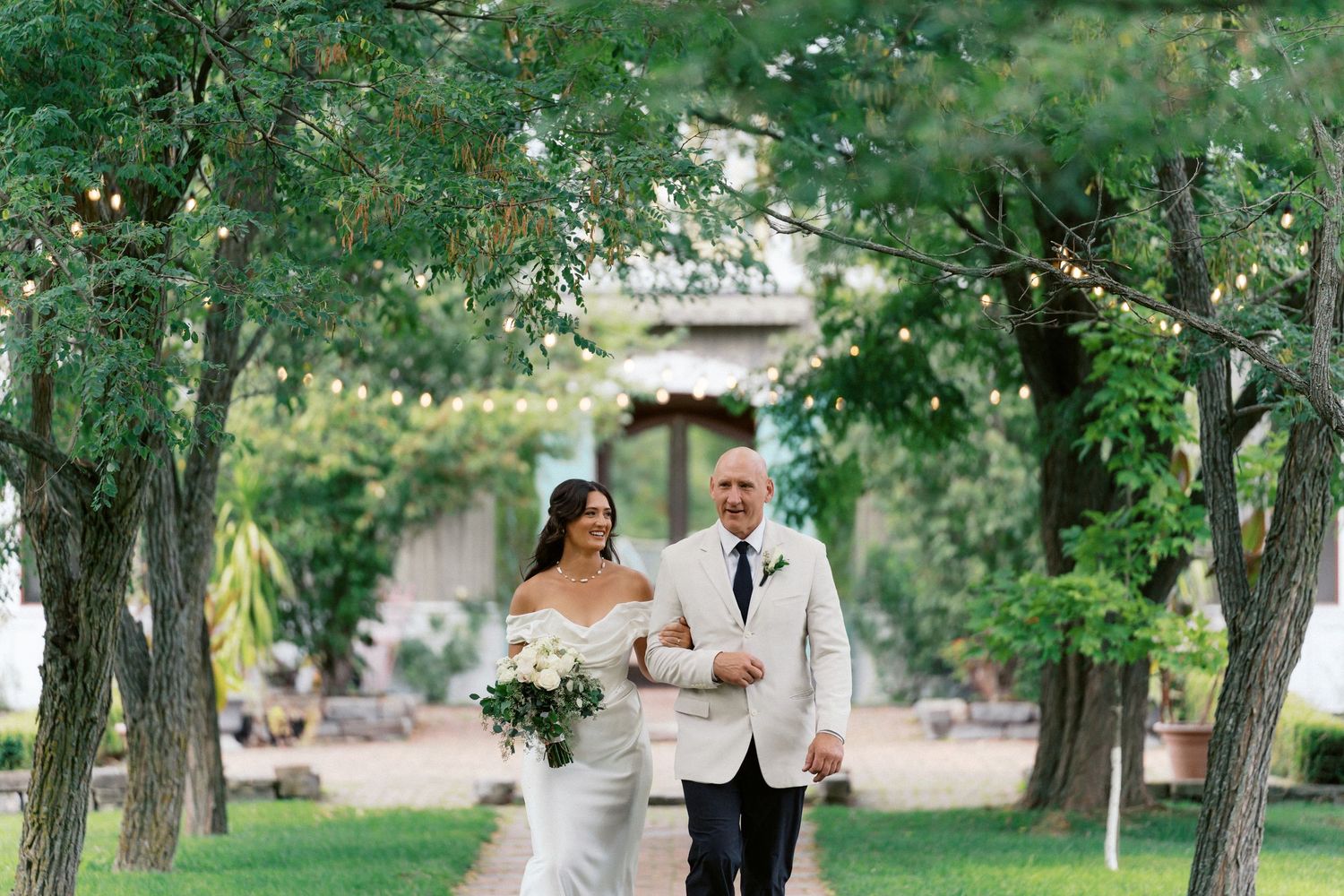 Couple walks together through a lush garden path during their wedding celebration.