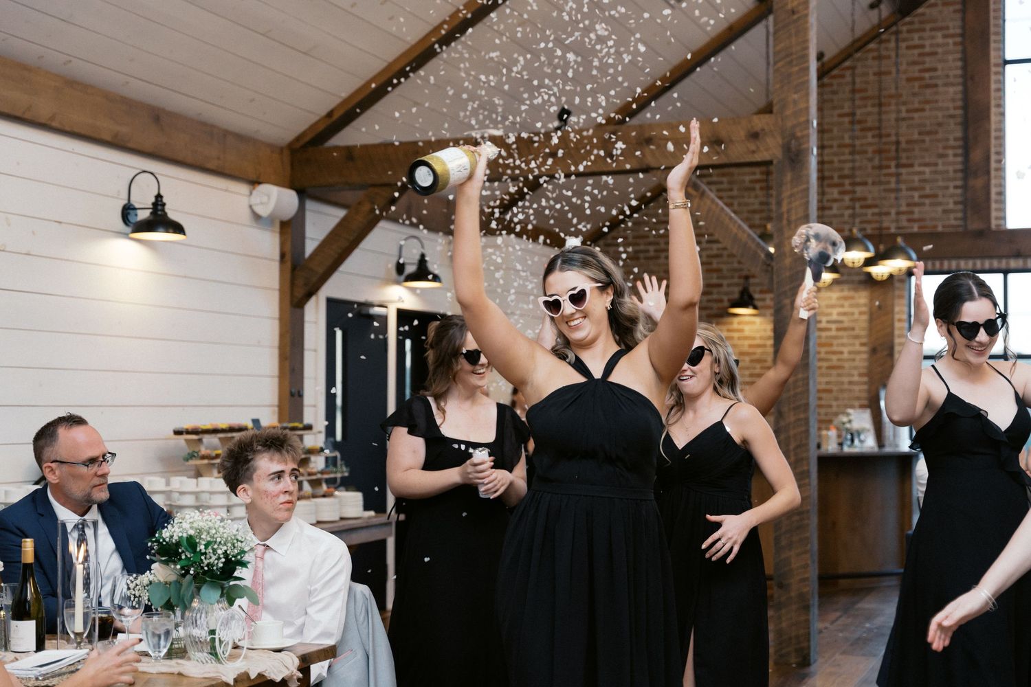 Wedding celebration with guests raising arms in joy inside rustic venue.