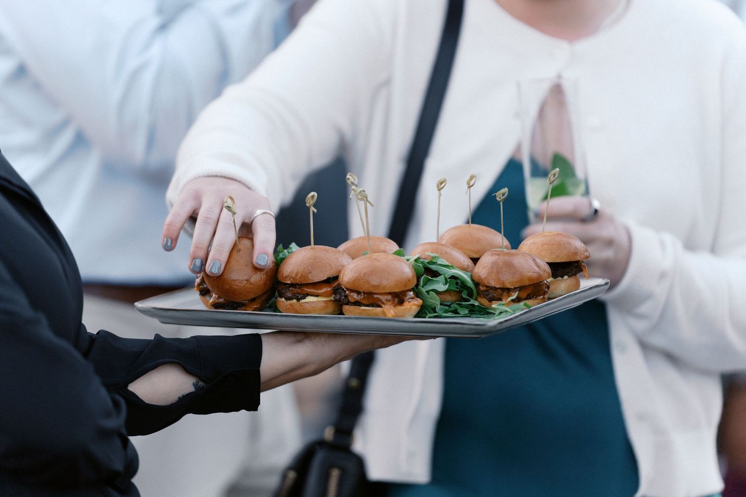 Catering staff serves appetizers on platters at an elegant wedding reception.