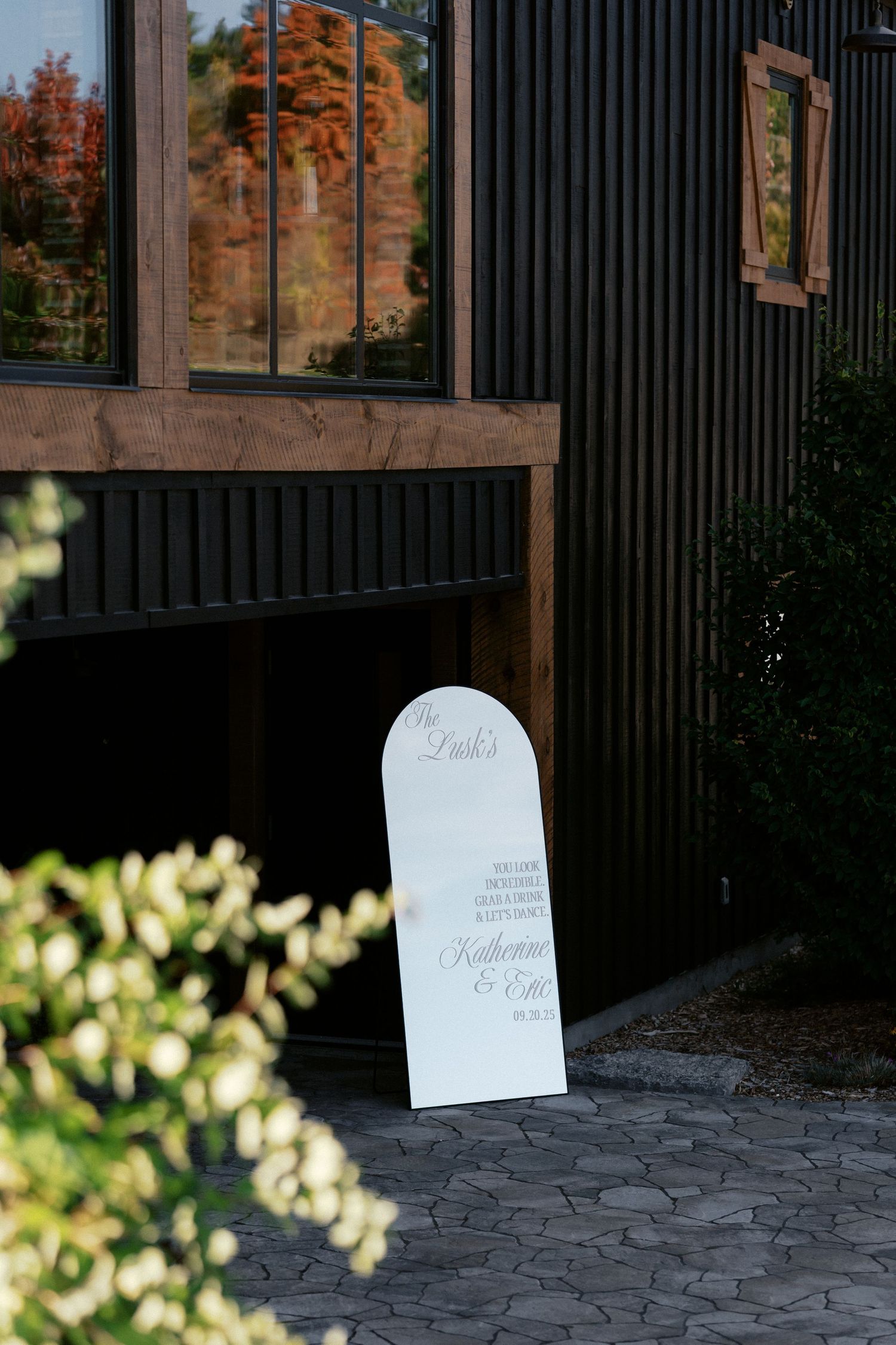 Black wooden panels create a dramatic backdrop with white signage in natural lighting.