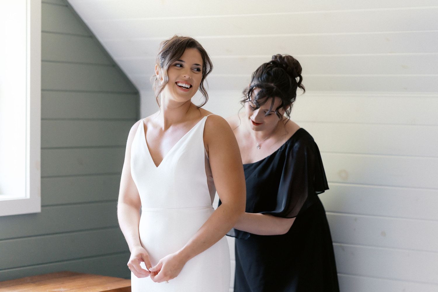 Wedding party members share joyful embraces and reactions during a first look reveal moment.