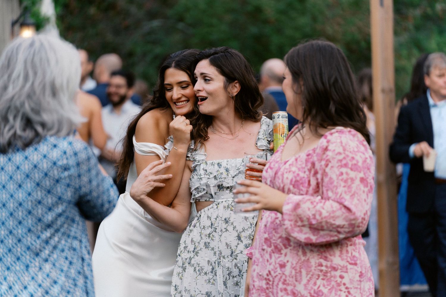 Wedding guests enjoying conversations and drinks at an outdoor summer reception.
