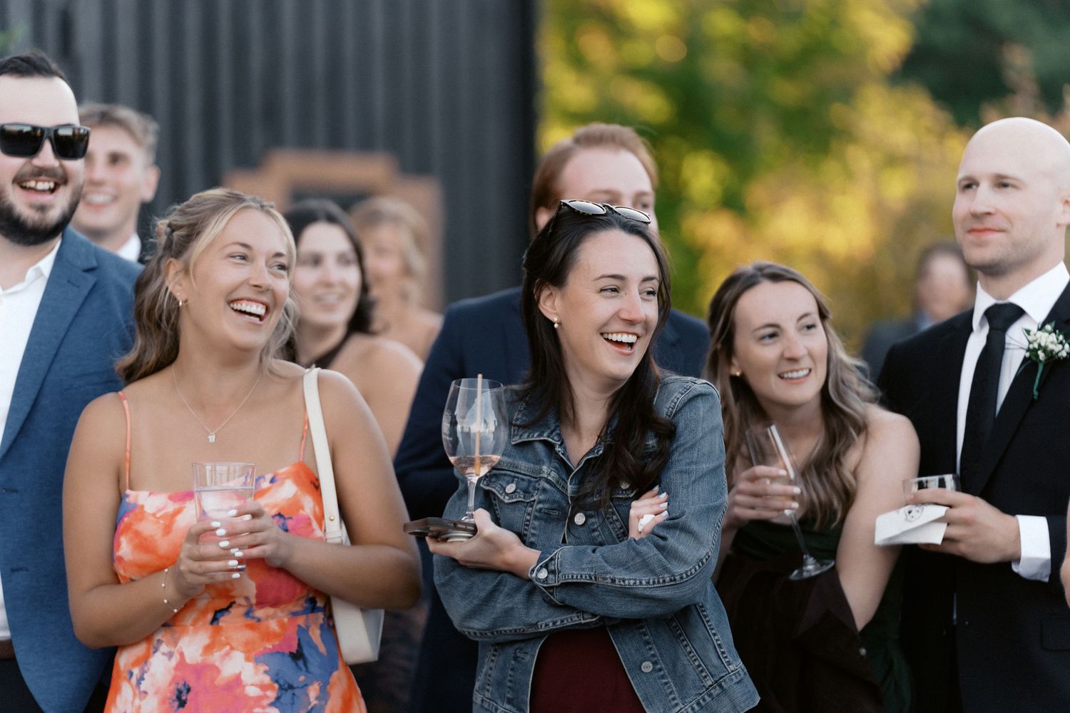 Wedding guests enjoying outdoor reception with natural fall scenery in background.
