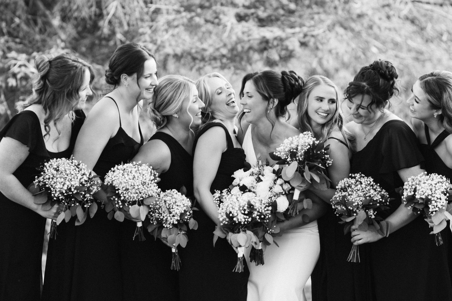 Black and white photo of bridesmaids holding bouquets and sharing joyful moments together.