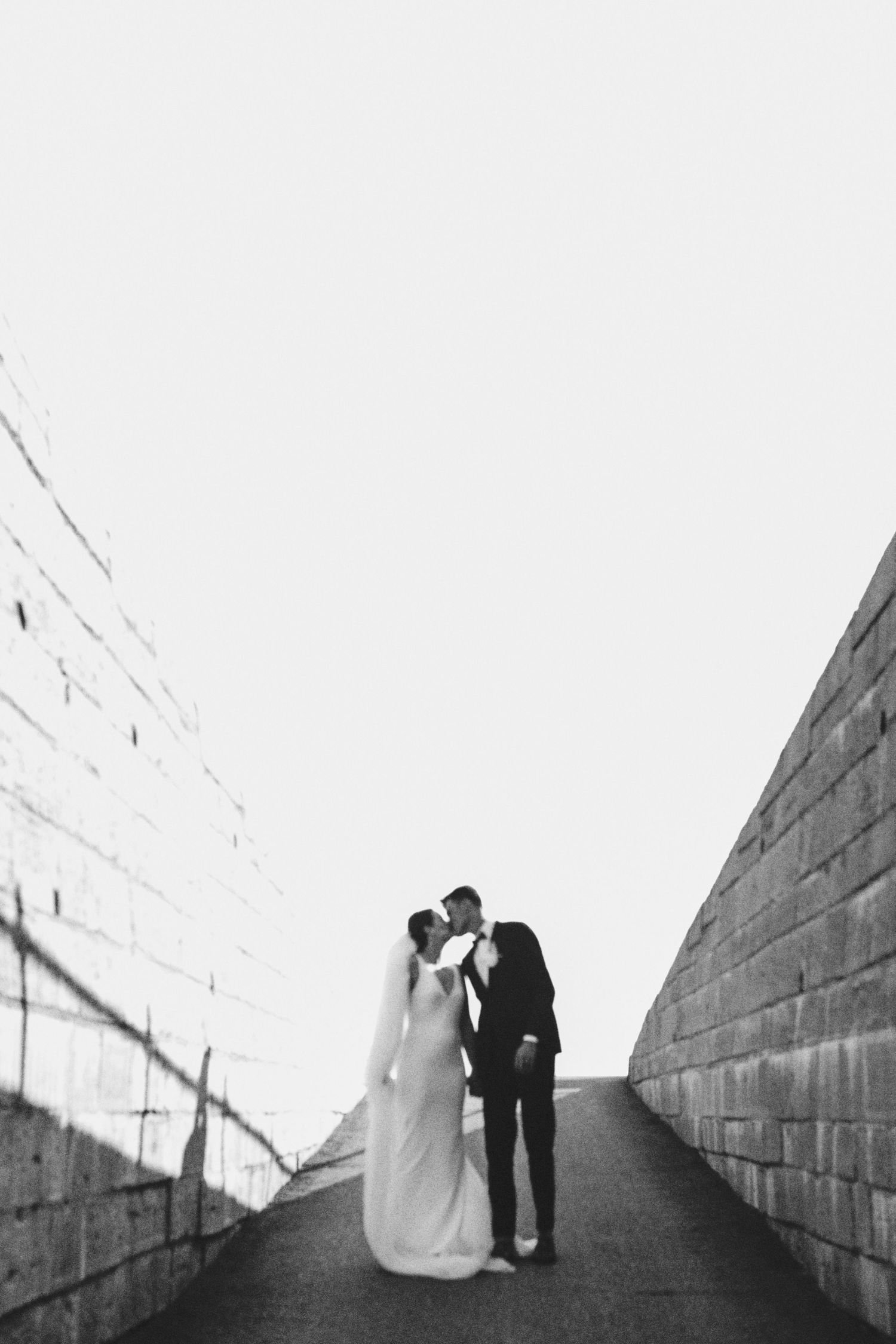 Minimalist black and white wedding photo on an urban incline with geometric walls.