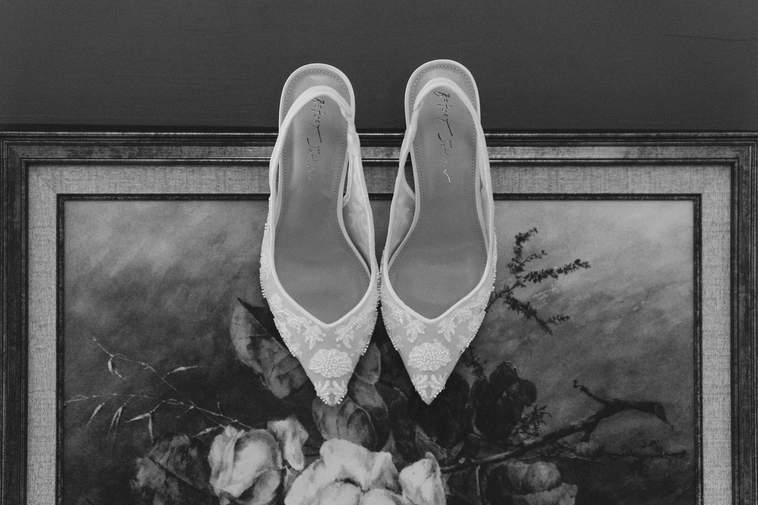 A series of black and white photographs showing vintage wedding shoes and formal attire arranged in elegant frames.