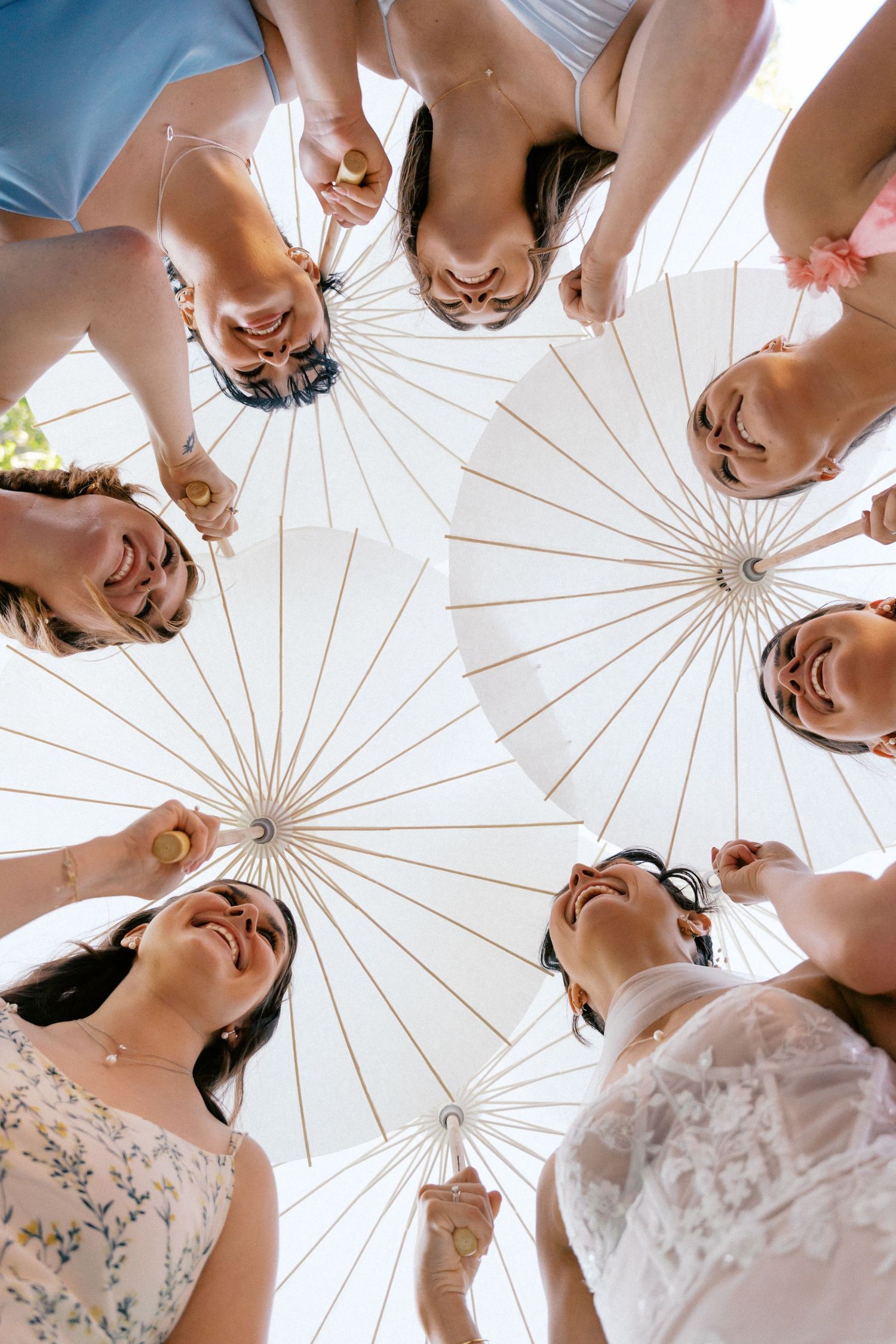 A creative low-angle photo showing a circle of bridesmaids looking down at the camera with joyful expressions.