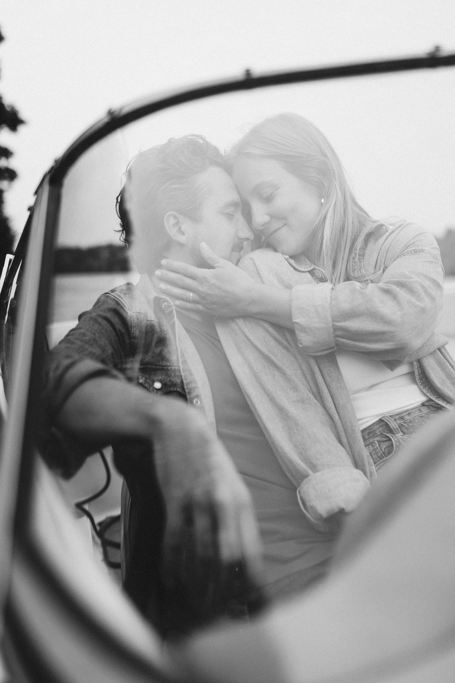 Intimate black and white photo of a tender moment captured through a car window.