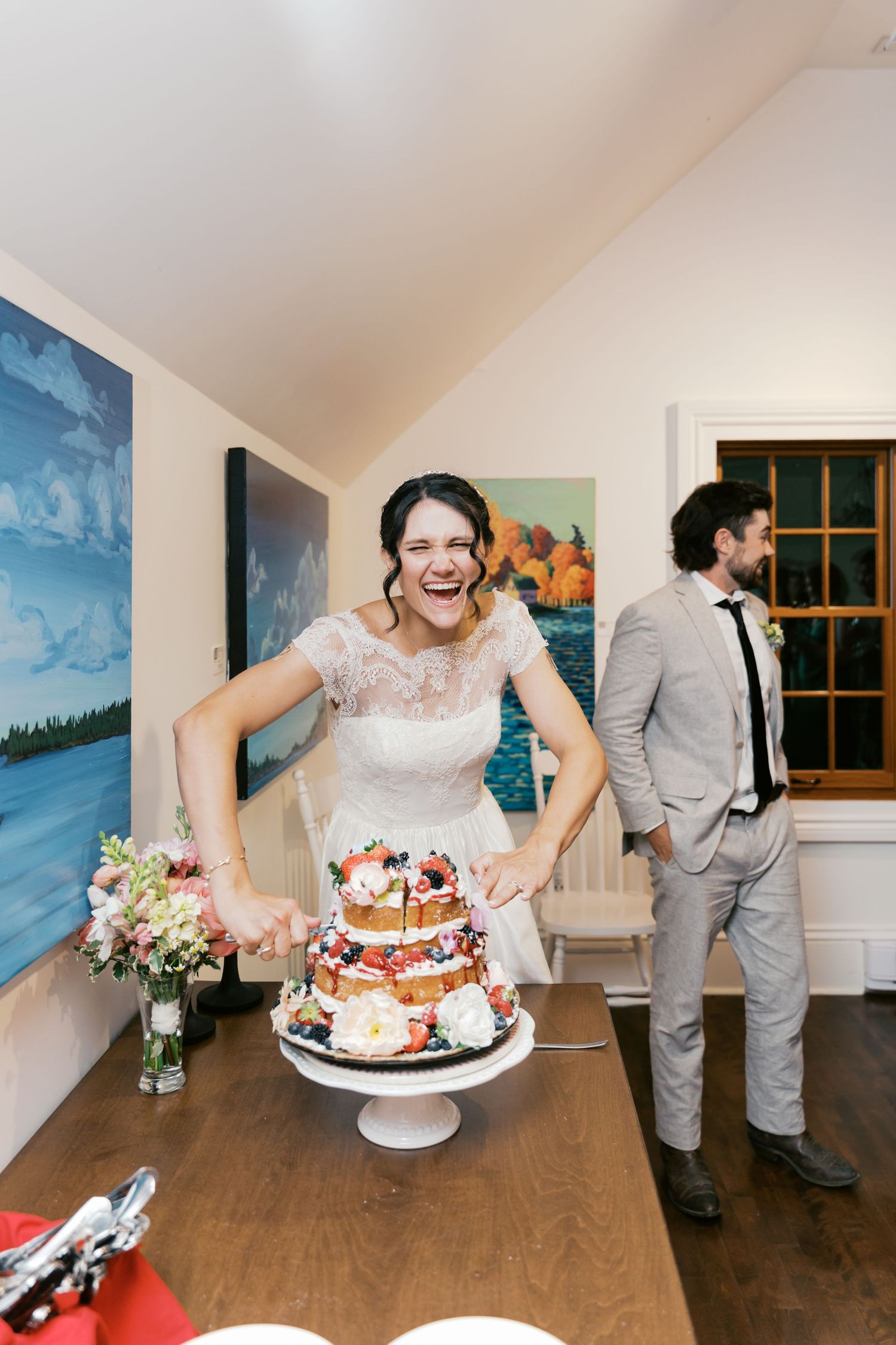 Candid moments of wedding cake cutting celebration in an indoor reception venue.