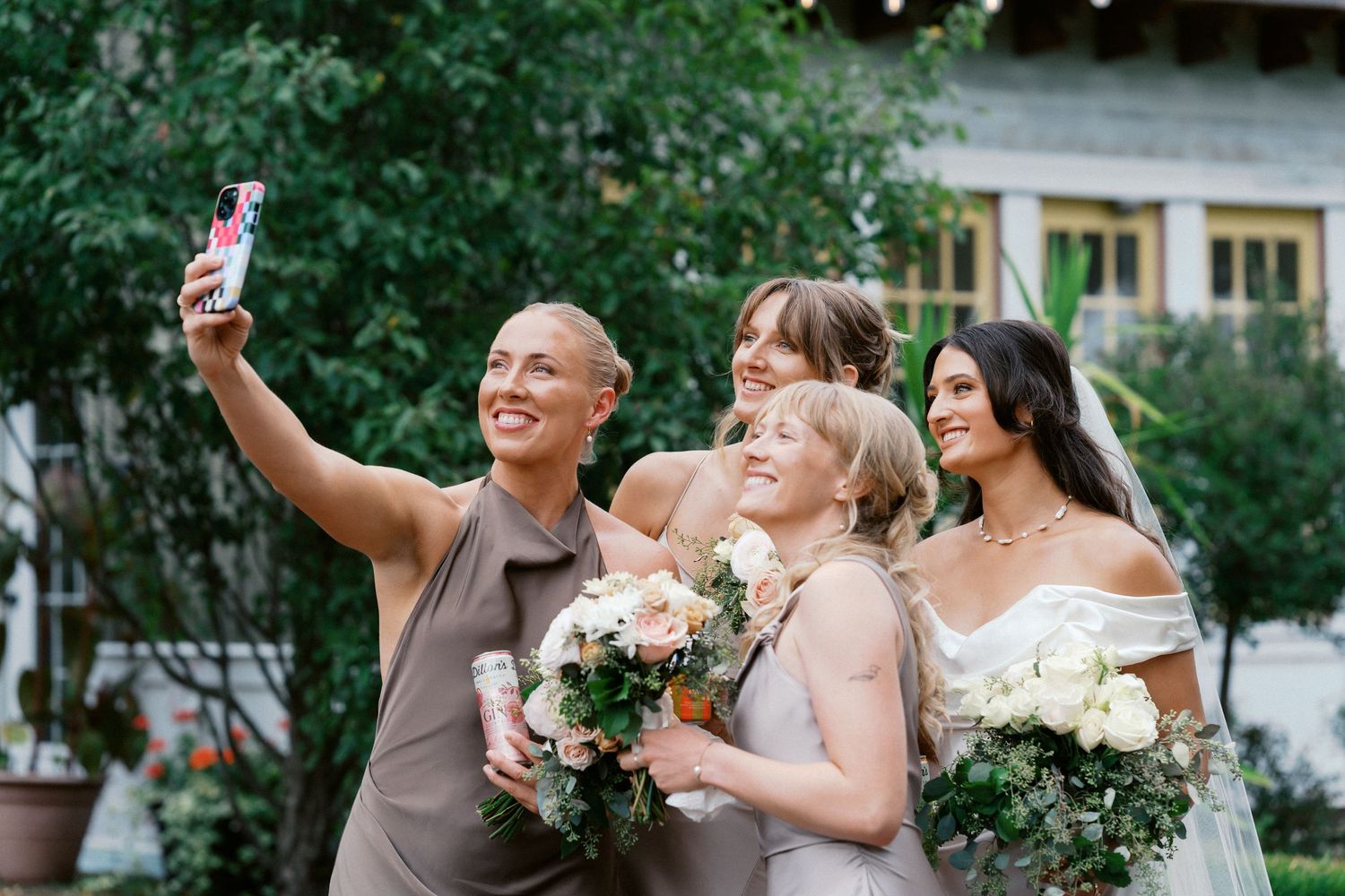 Wedding party members celebrate with champagne outdoors in a garden setting.