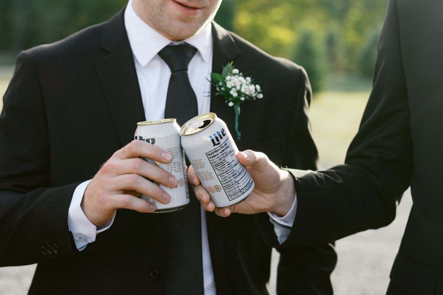 Wedding party members in formal attire holding white beverage cans.