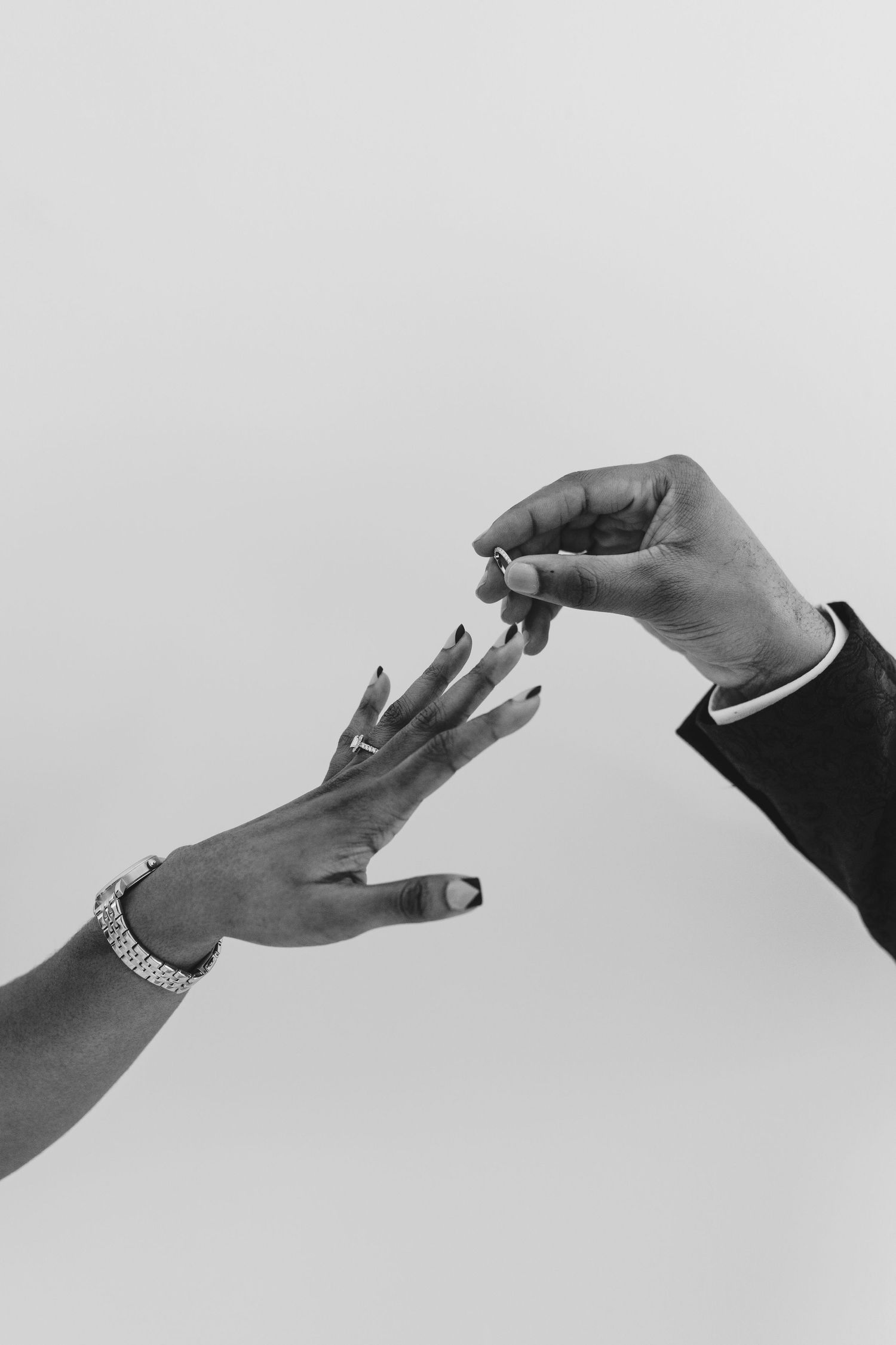 Black and white close-up of hands exchanging a wedding ring.