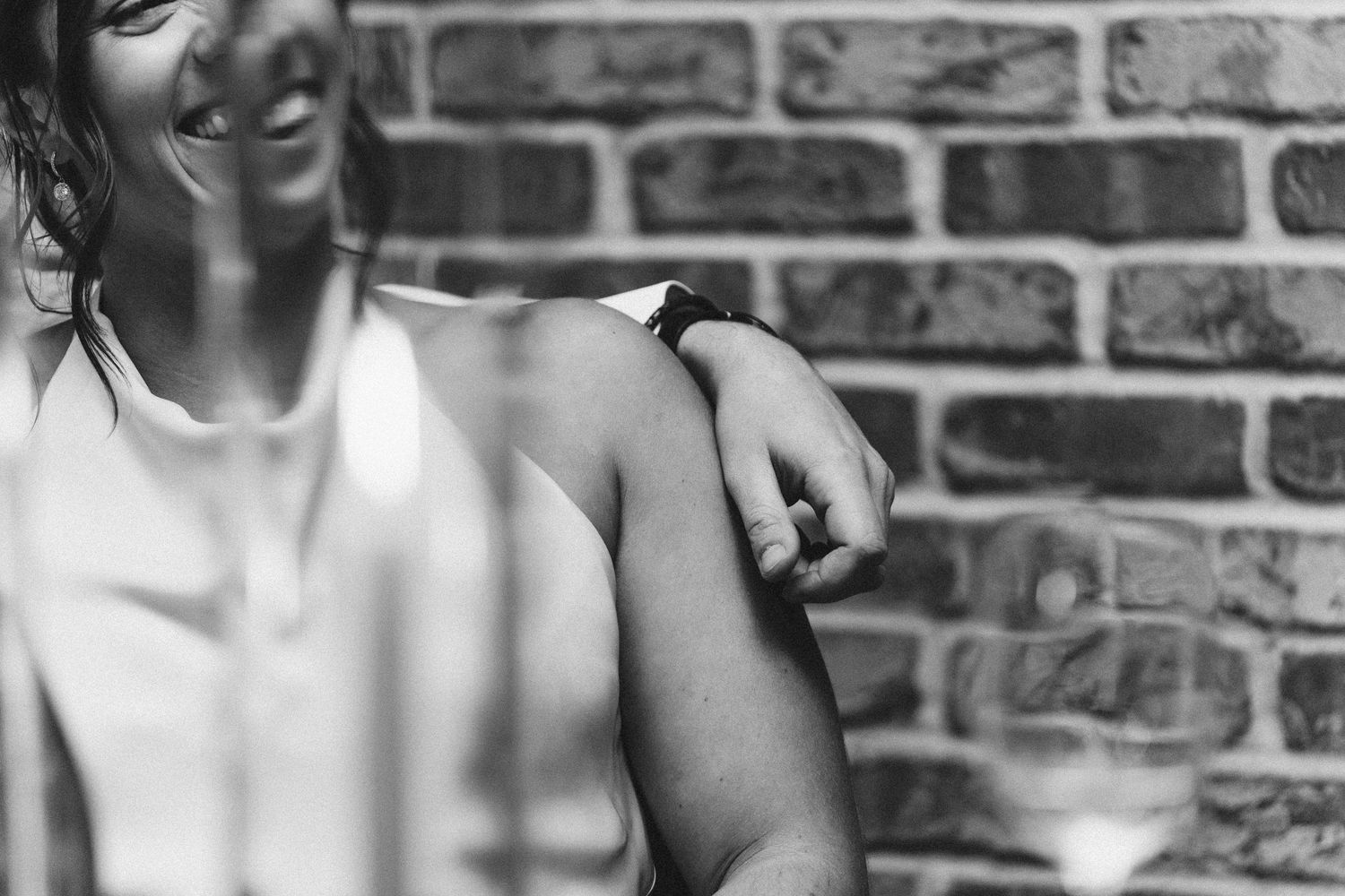 Black and white portrait photo against a brick wall with dramatic lighting and shadow effects.