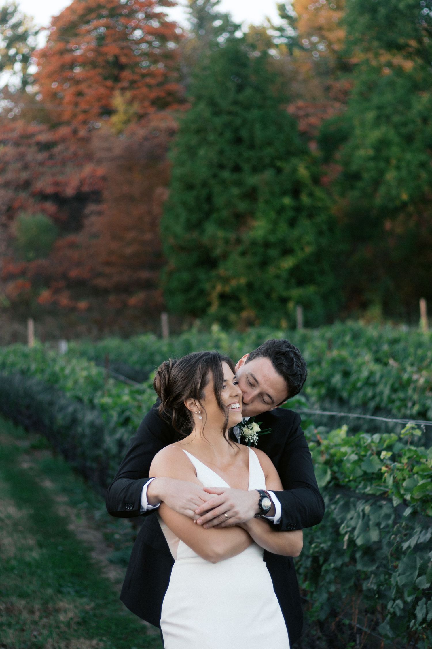 Romantic couple embracing in vineyard during autumn sunset.