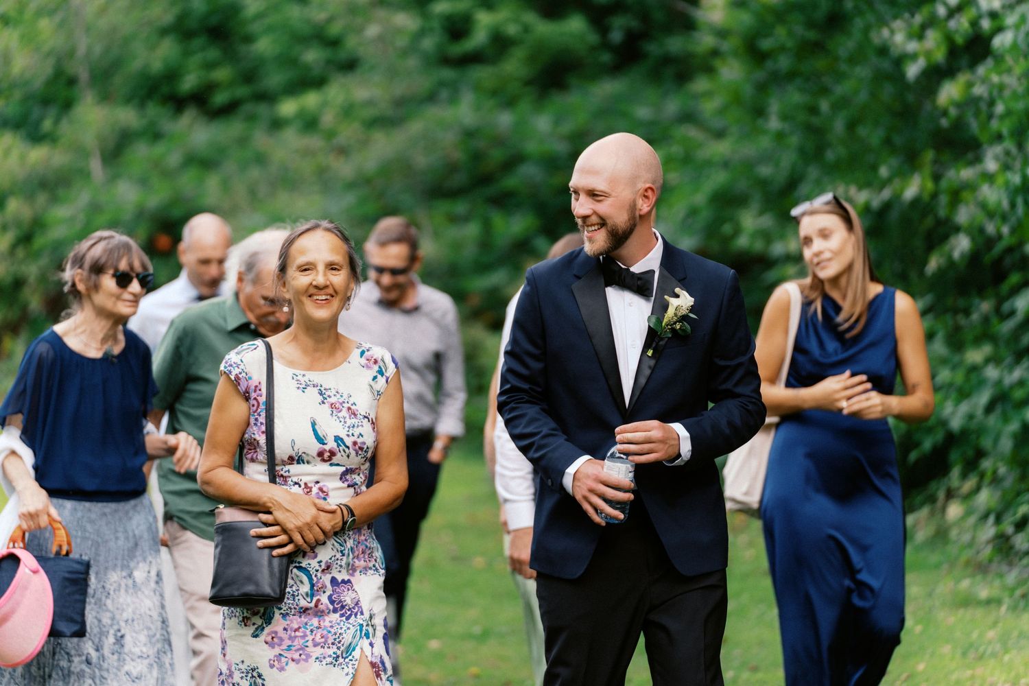 Wedding guests mingle and laugh together during an outdoor garden reception celebration.