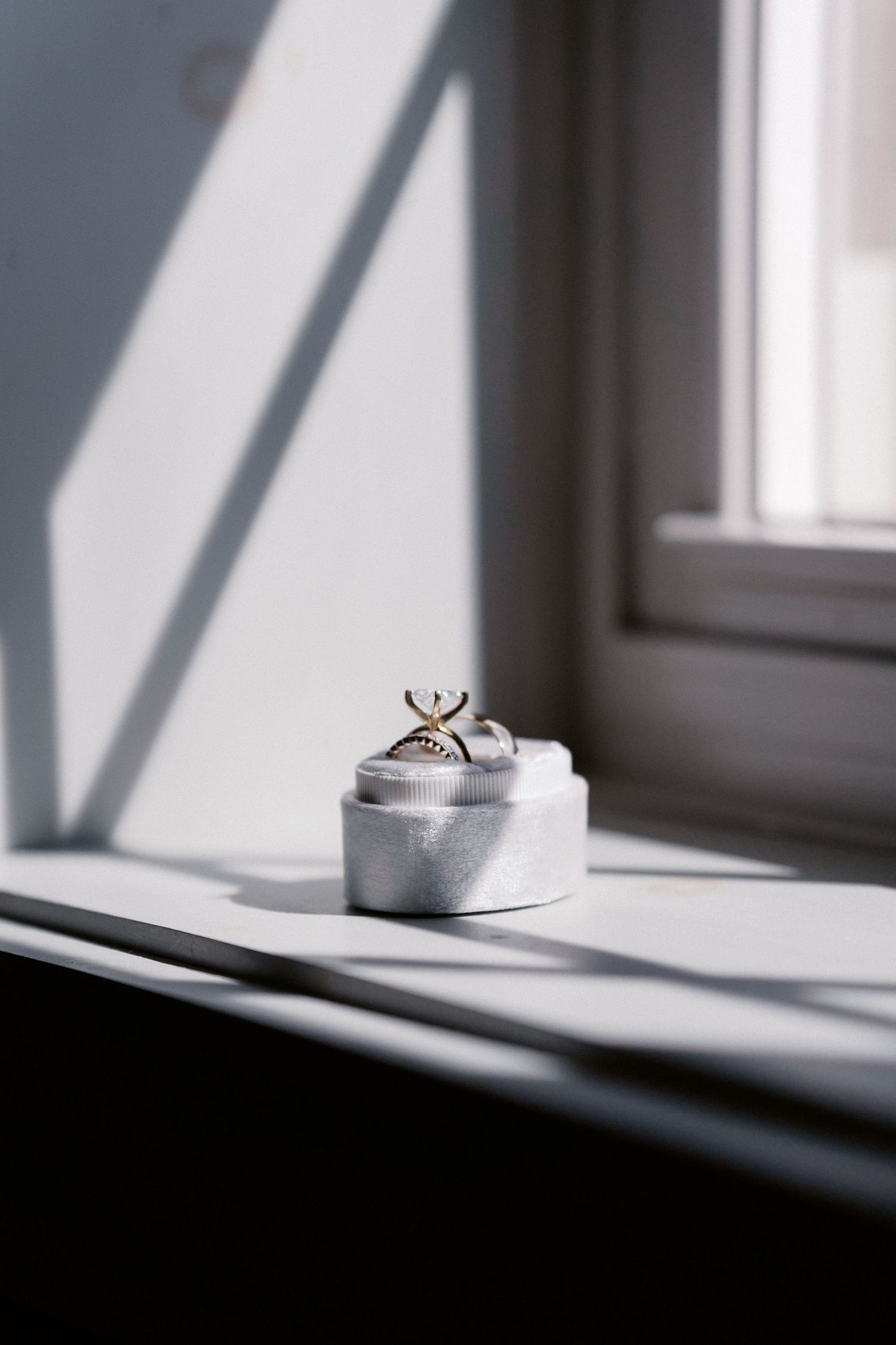 Wedding rings casting shadows on windowsill in natural light.