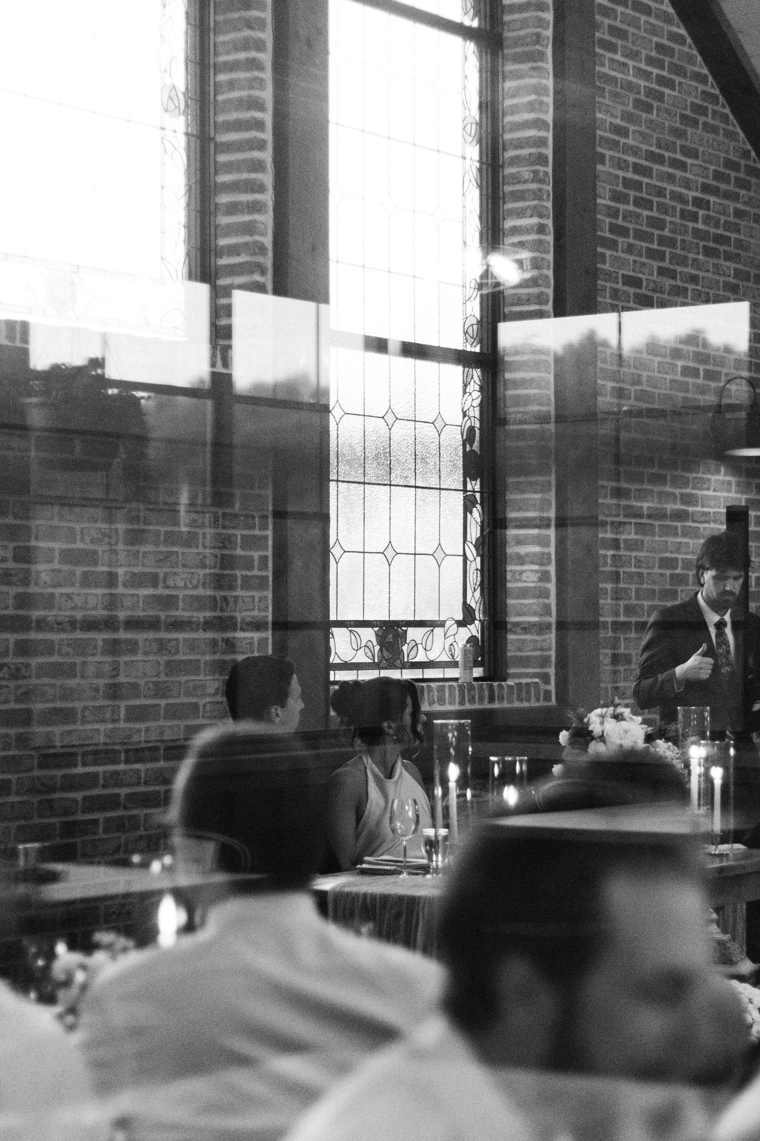 Black and white reception photo showing brick walls and window details in an indoor venue.