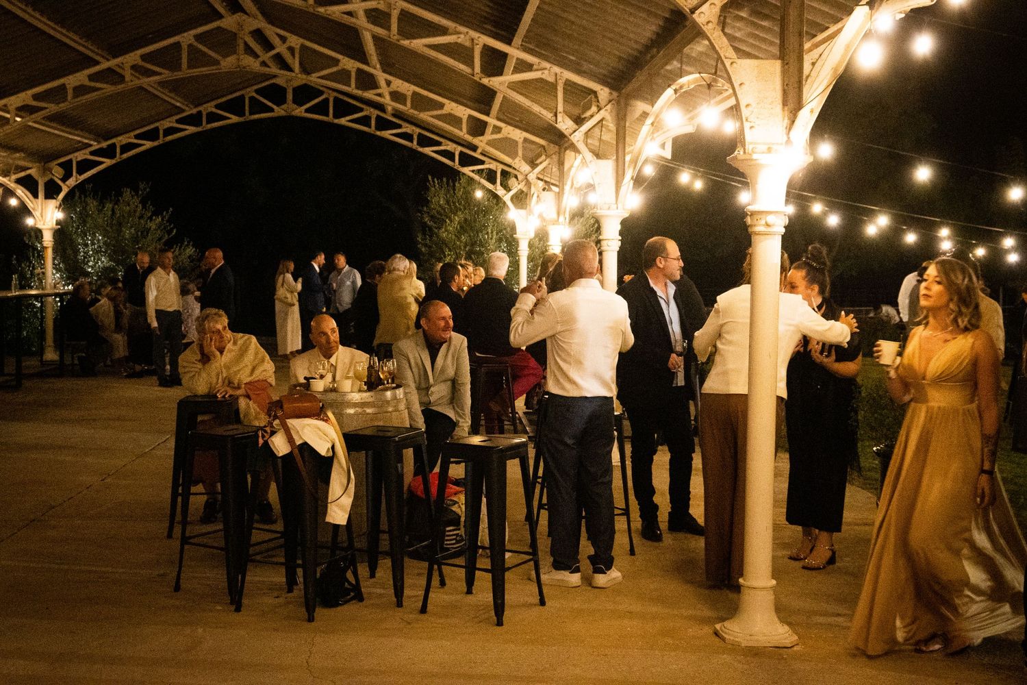 Outdoor evening wedding reception with string lights creating romantic ambiance.