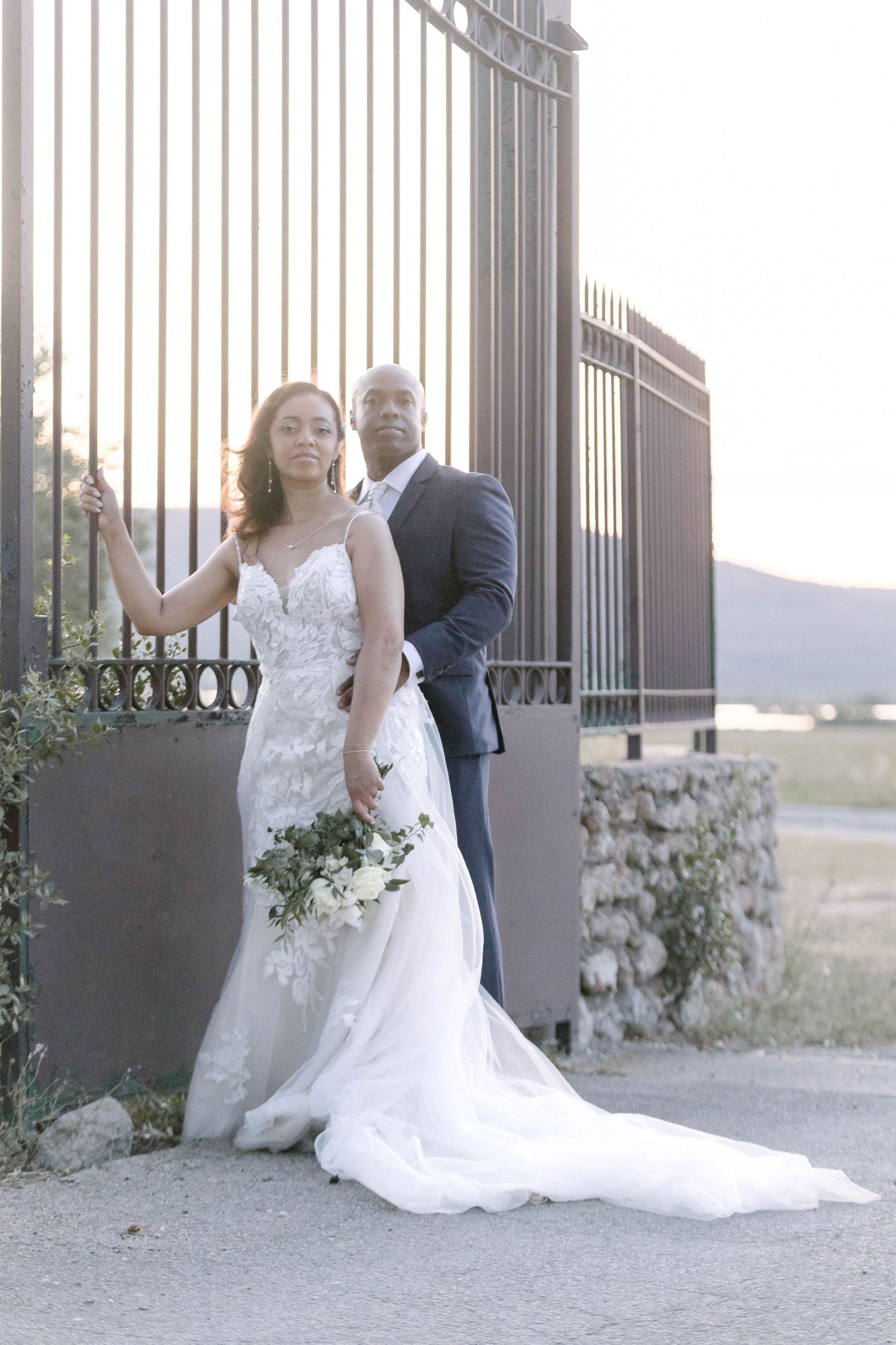 A couple poses for their wedding photo against an elegant iron gate backdrop.