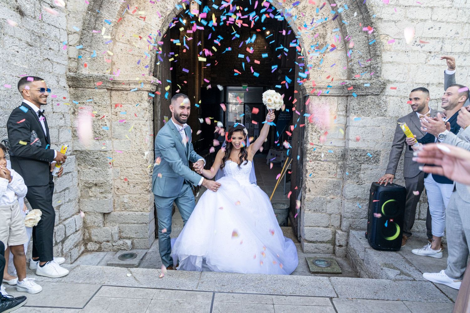Celebratory confetti moment outside a historic church after a wedding ceremony.