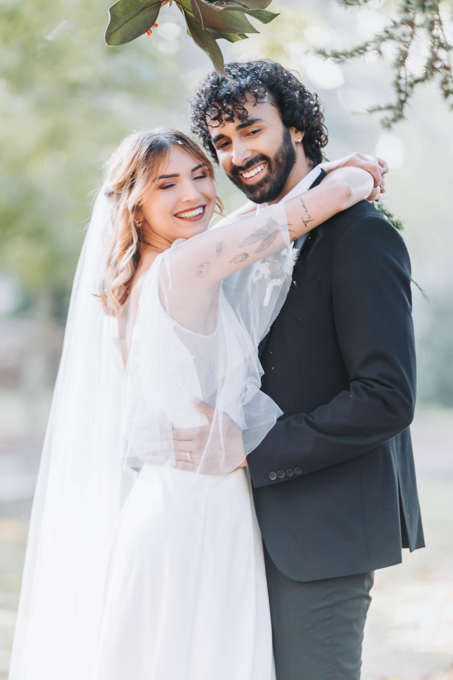 Joyful wedding couple sharing loving moments in a sun-drenched outdoor setting.