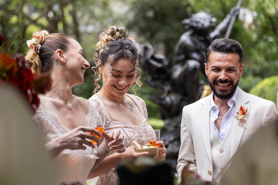 Joyful wedding celebration with guests sharing drinks and laughter in a garden setting.