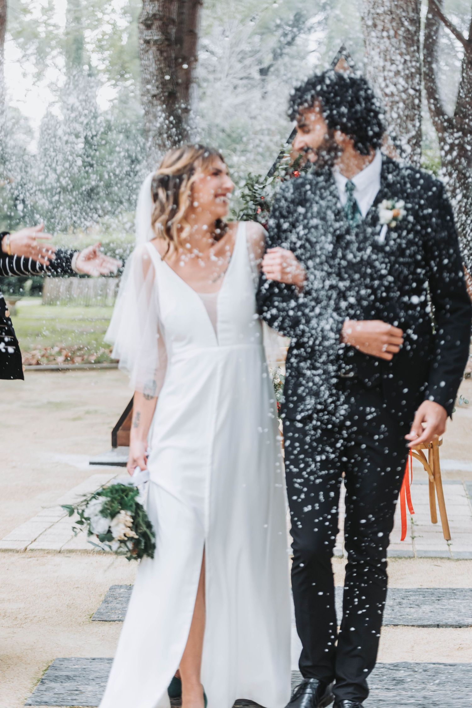 Newlyweds share joyful moment in falling snow during winter wedding celebration.