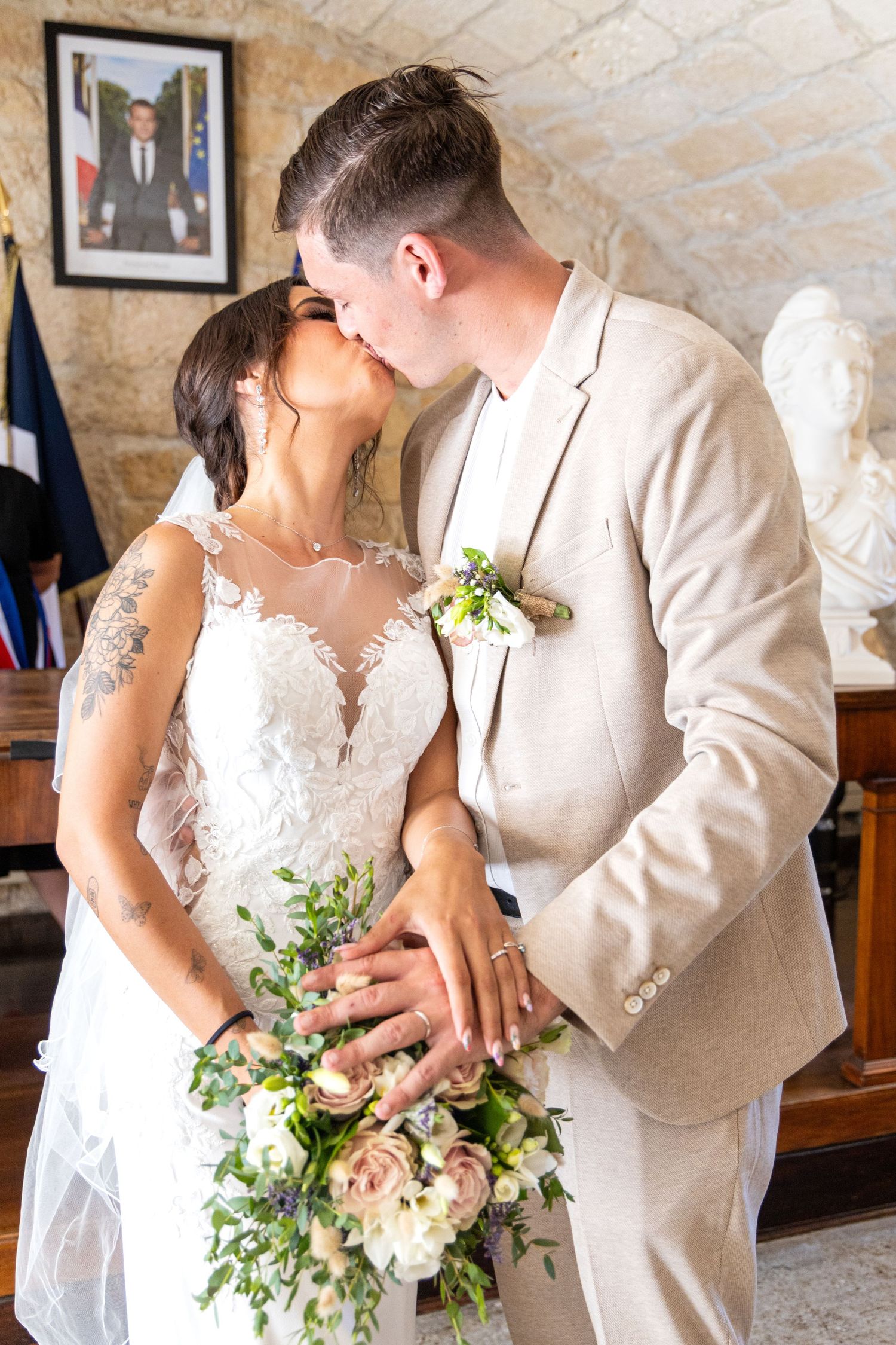 Intimate wedding moments with white lace dress and beige suit in stone interior.