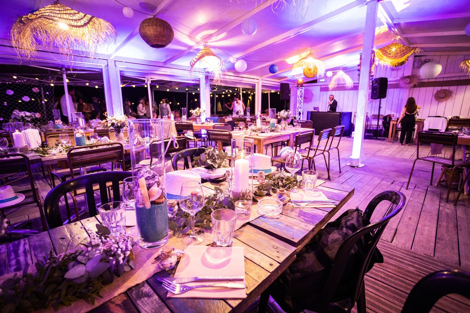 Wedding reception venue decorated with purple lighting and elegant table settings.