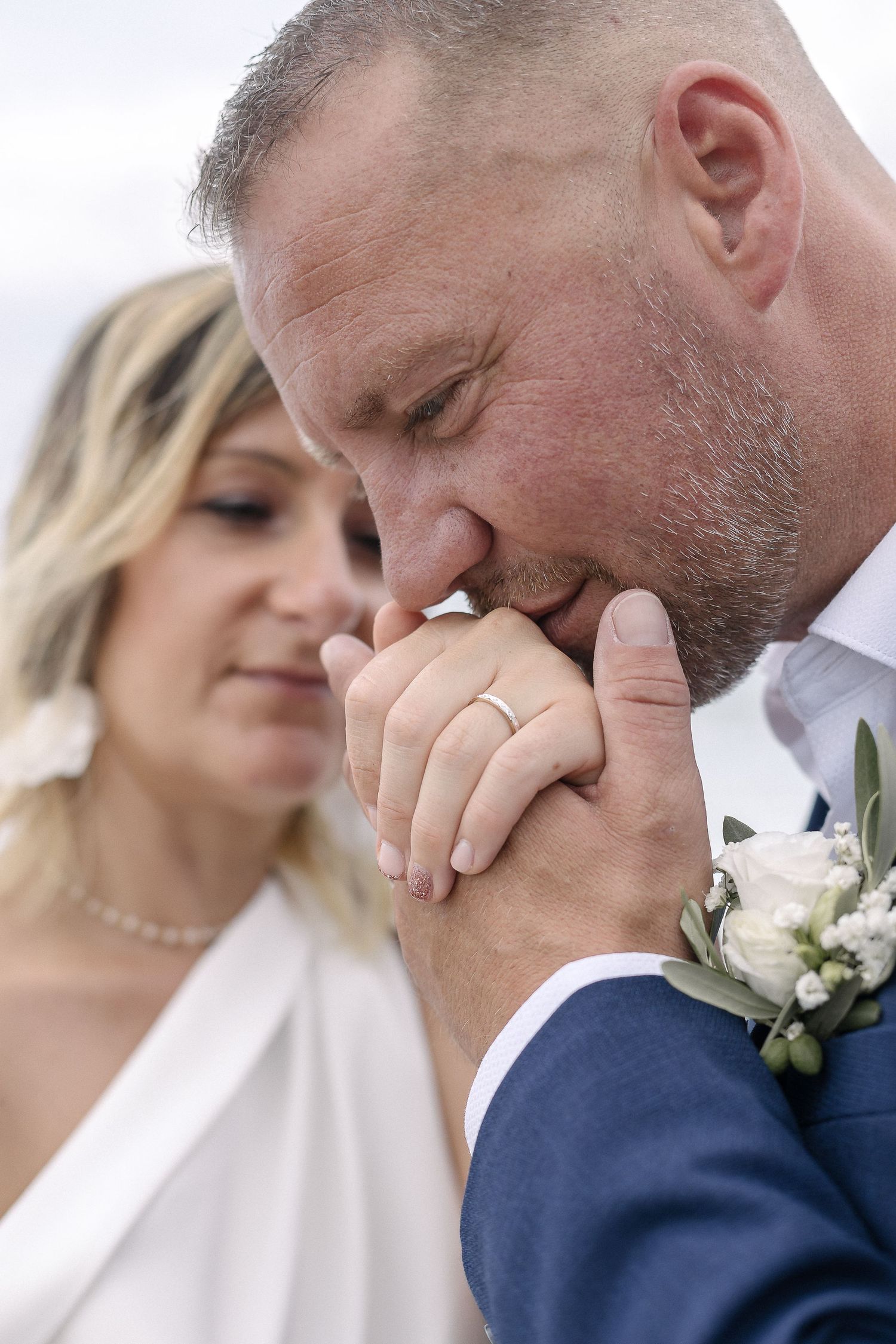 Emotional wedding moment captured in soft, intimate close-up by the ocean.