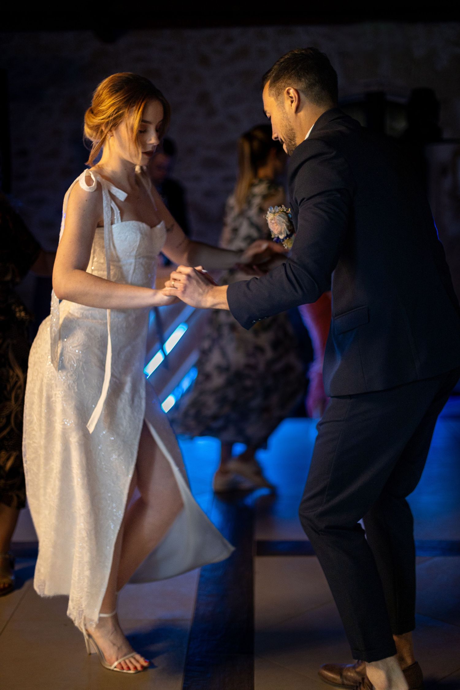 Couple dancing together under moody blue lighting at a wedding reception.