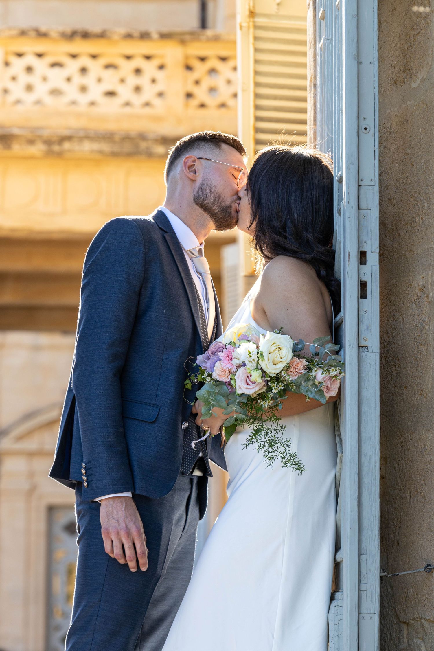 Intimate wedding moment captured under ornate architectural columns.