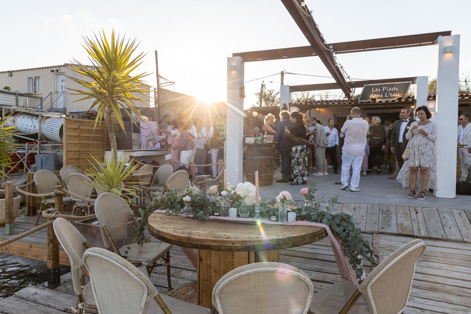 Wedding guests mingling at sunset outdoor reception with coastal views.