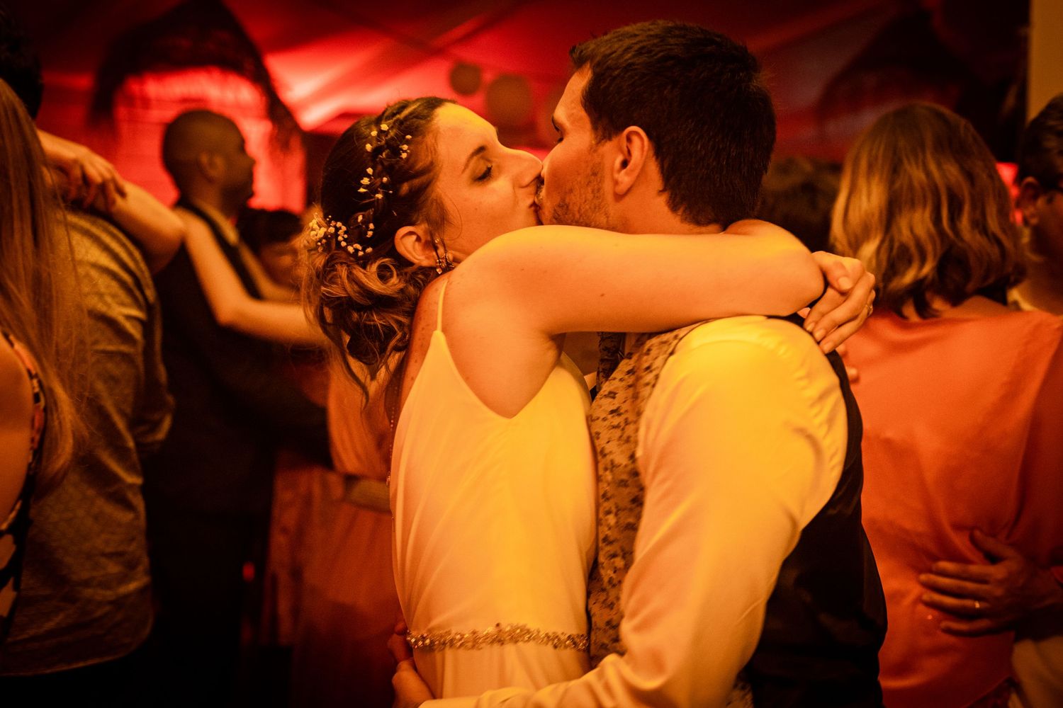 Wedding reception dance floor bathed in warm red lighting.