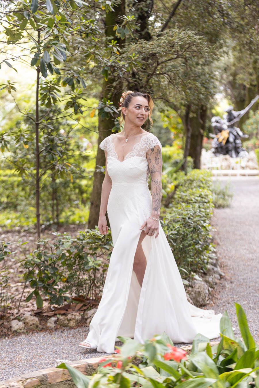 Wedding dress with lace details photographed in a lush garden pathway.