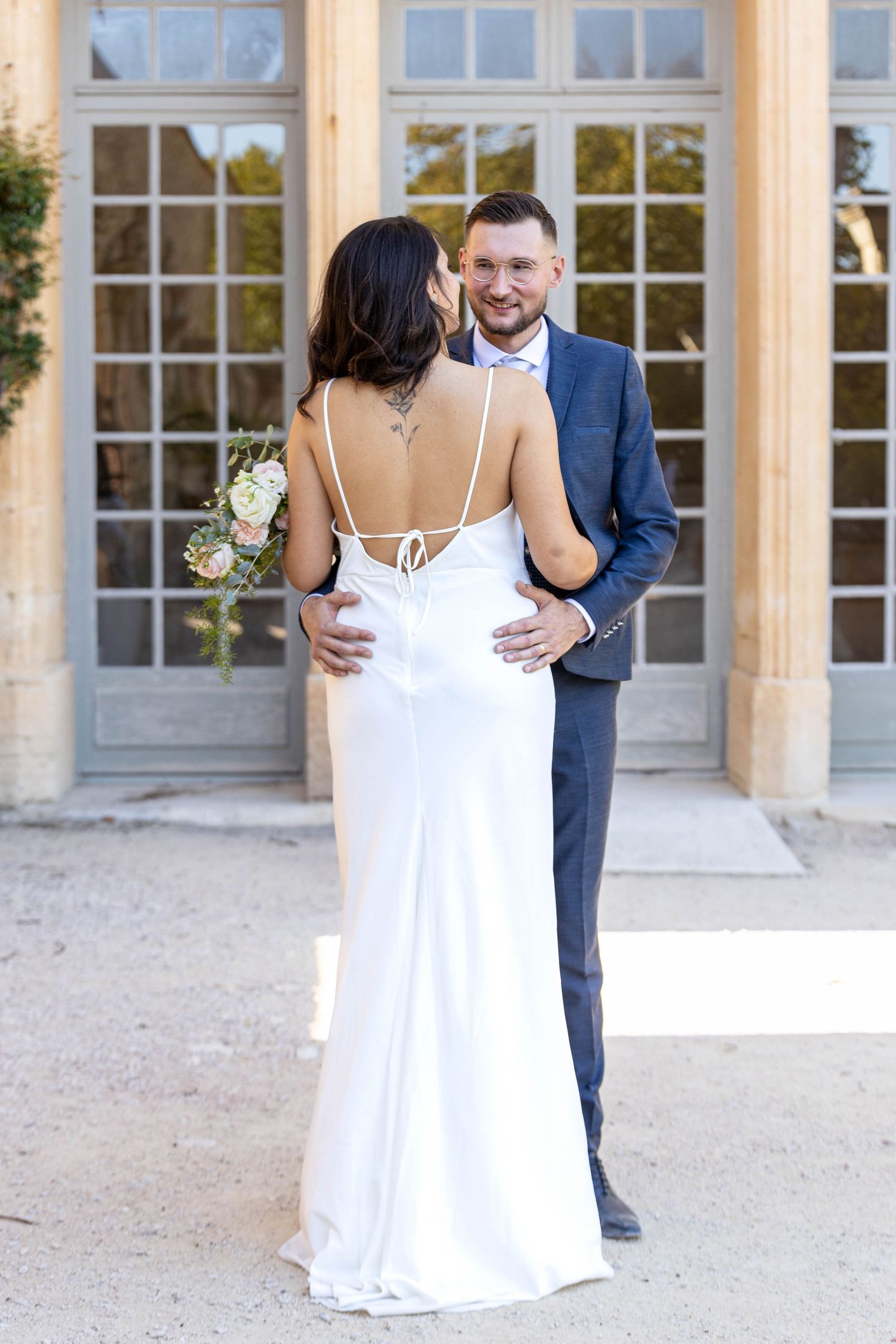 Romantic newlyweds pose together in casual wedding portraits outdoors.