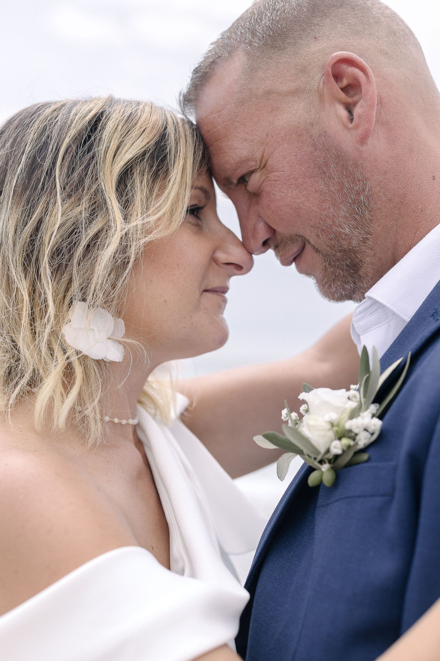 Close-up wedding portraits capturing tender moments against bright coastal backdrop.