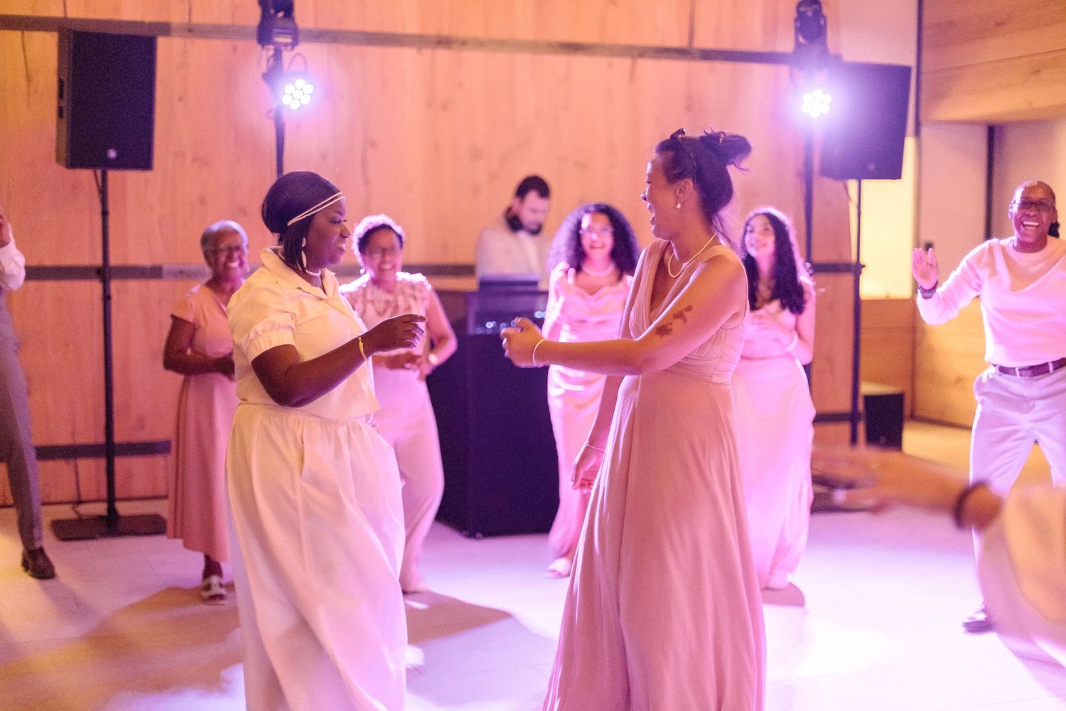 Wedding guests dancing and celebrating in all-white attire at reception.