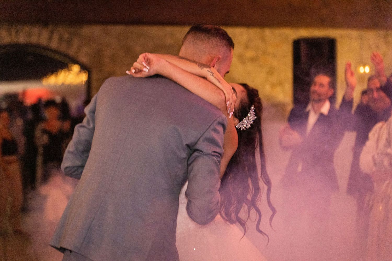 Couple sharing an intimate slow dance at their wedding reception with warm lighting and decorative elements.