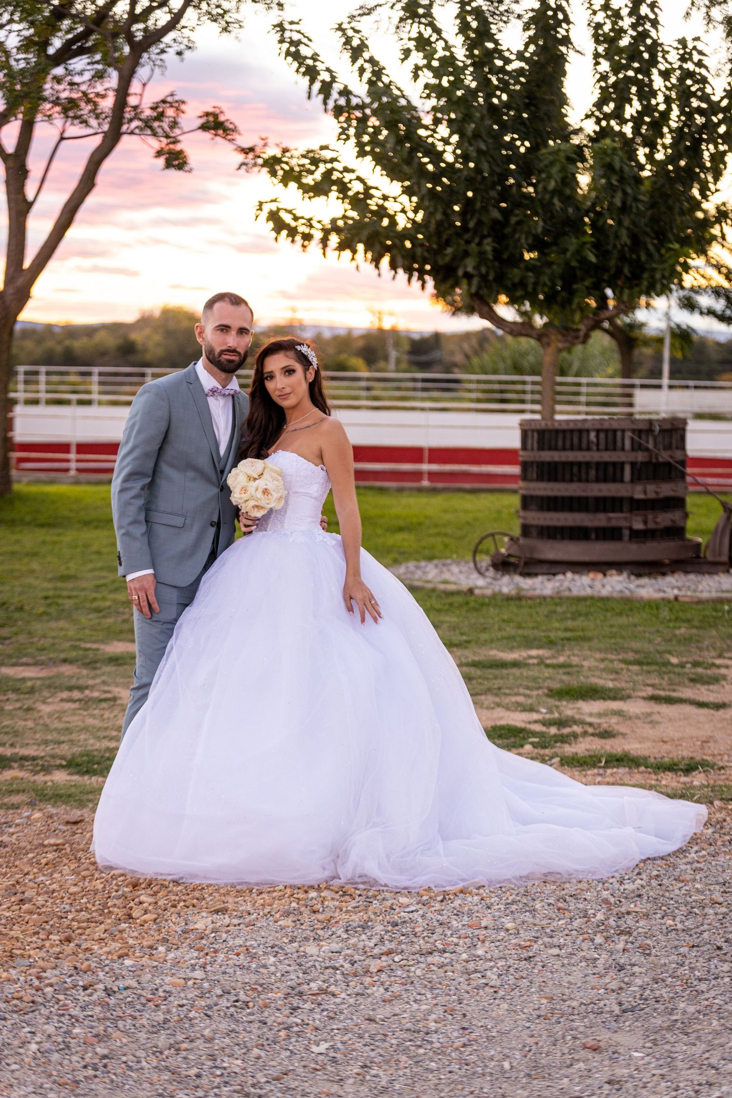 Wedding portraits on gravel path with rustic wooden crates and trees in background.
