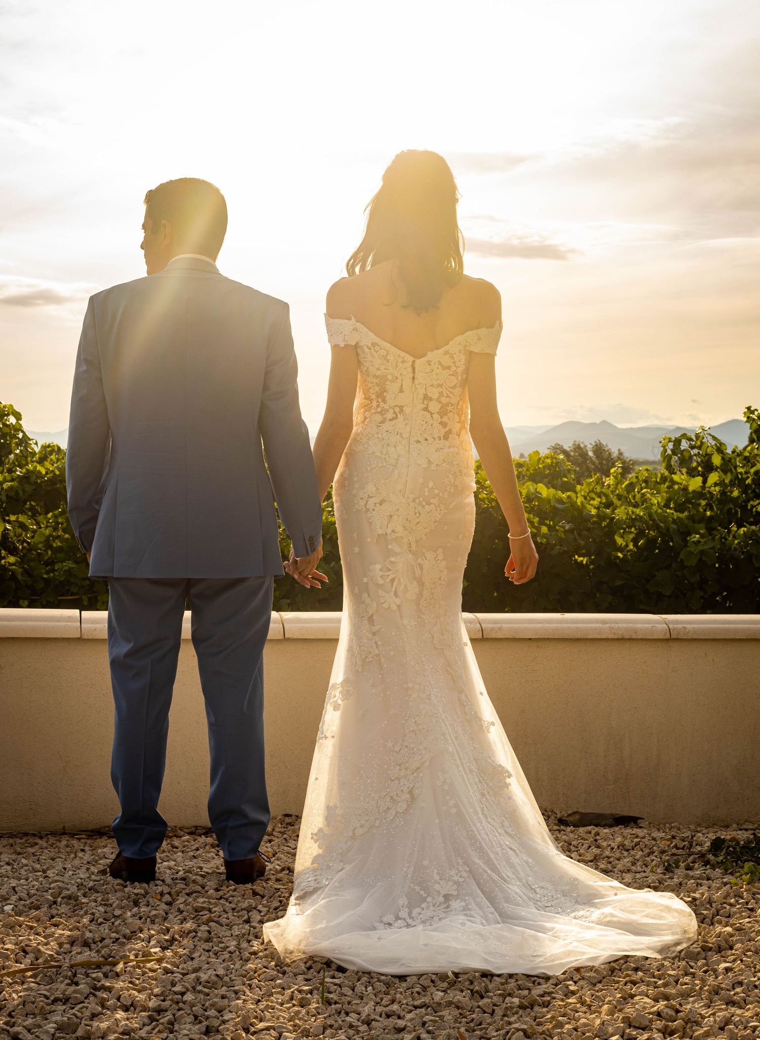 Silhouetted couple at sunset overlooking vineyard landscape.