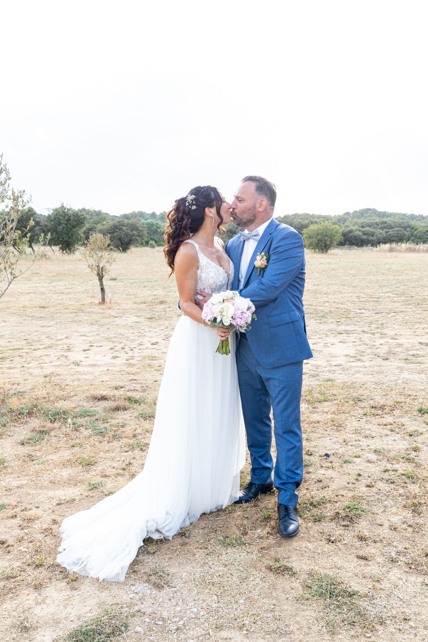 A romantic countryside wedding photo with rolling hills in background.