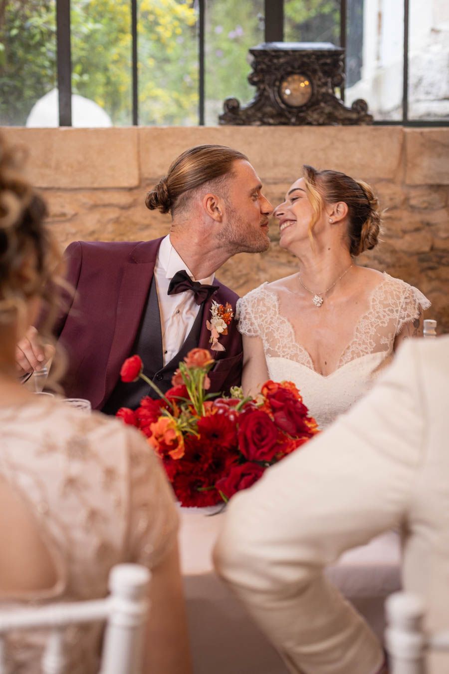 Romantic moment at wedding reception with red and orange floral bouquet details.