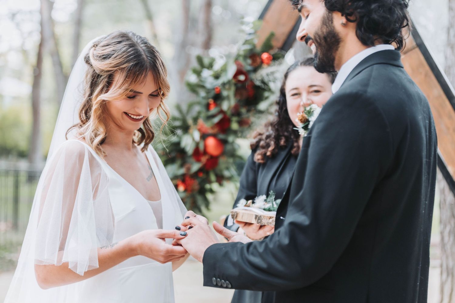 Couple shares intimate moment during ring exchange at outdoor winter ceremony.