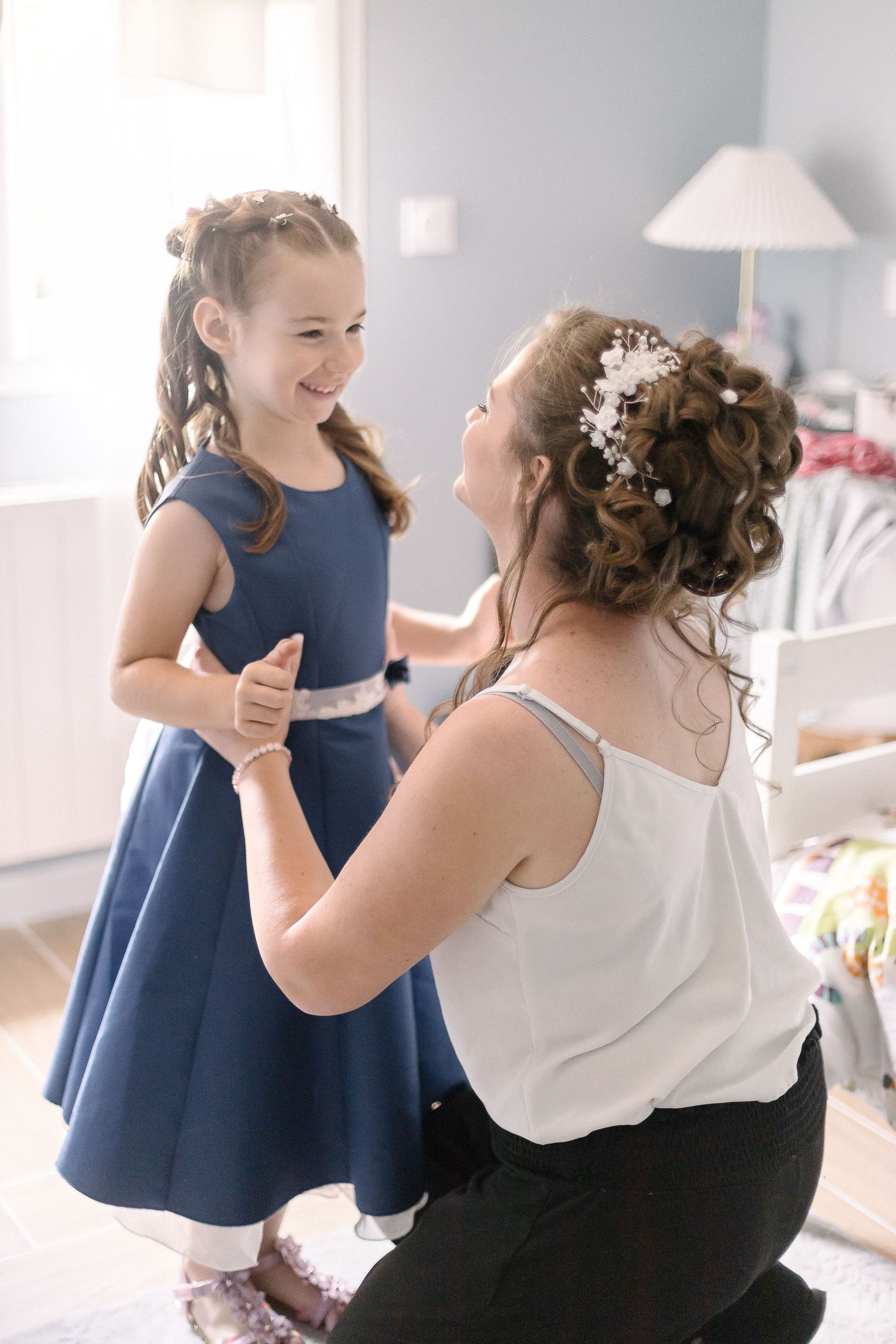 Heartwarming moment between a bride and young girl in navy blue dress.