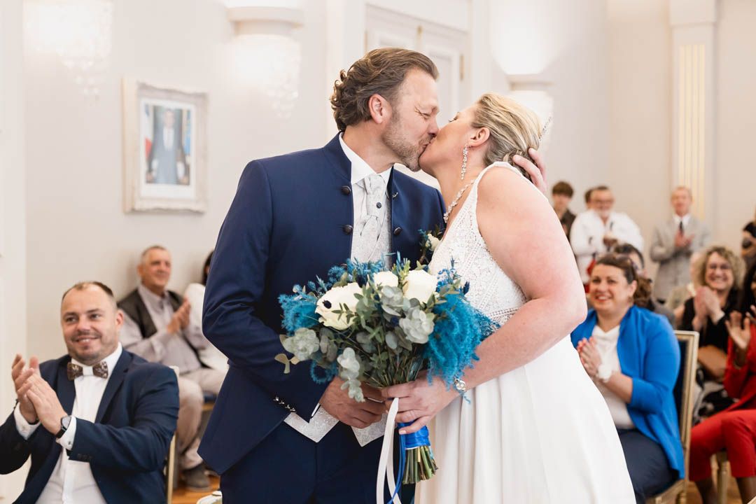 Wedding ceremony in bright white room with guests watching happy couple.