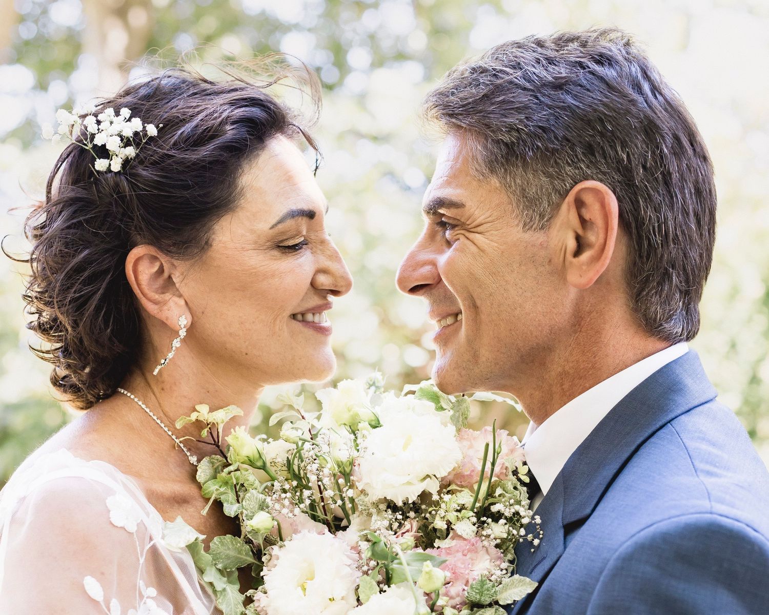 Intimate close-up of newlyweds sharing tender moment with white floral bouquet.